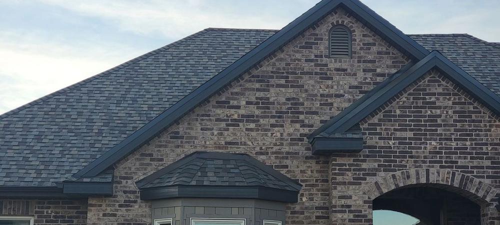Brick home with a new gray roof installed by Legend Roofing in Utah